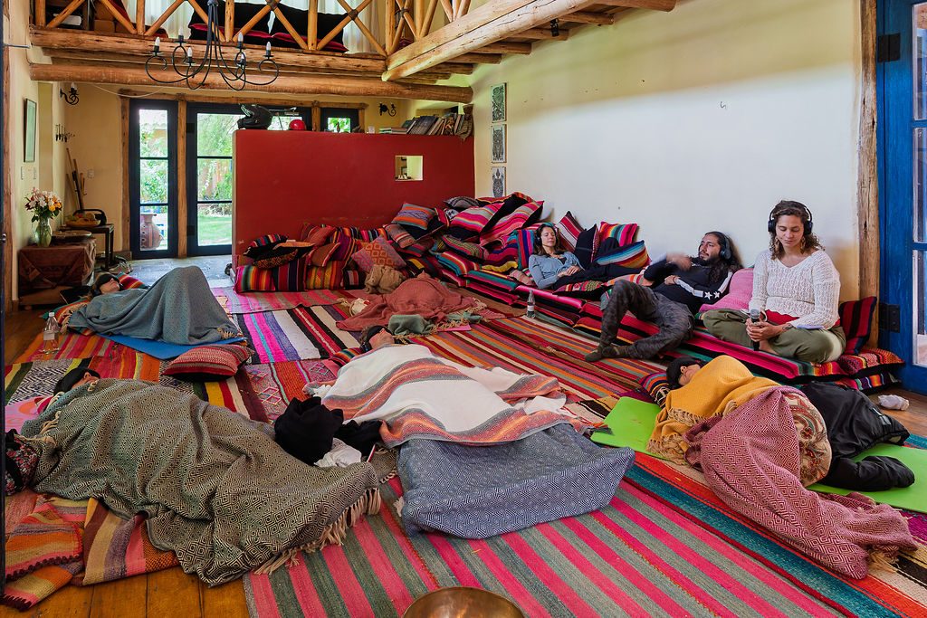 The group lies on cushions in the shala during a breathwork session