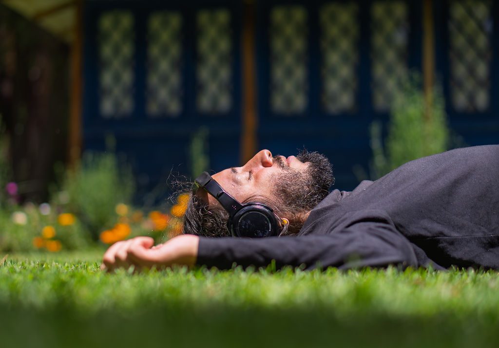 A participant lies on the lawn breathing deeply with headphones on