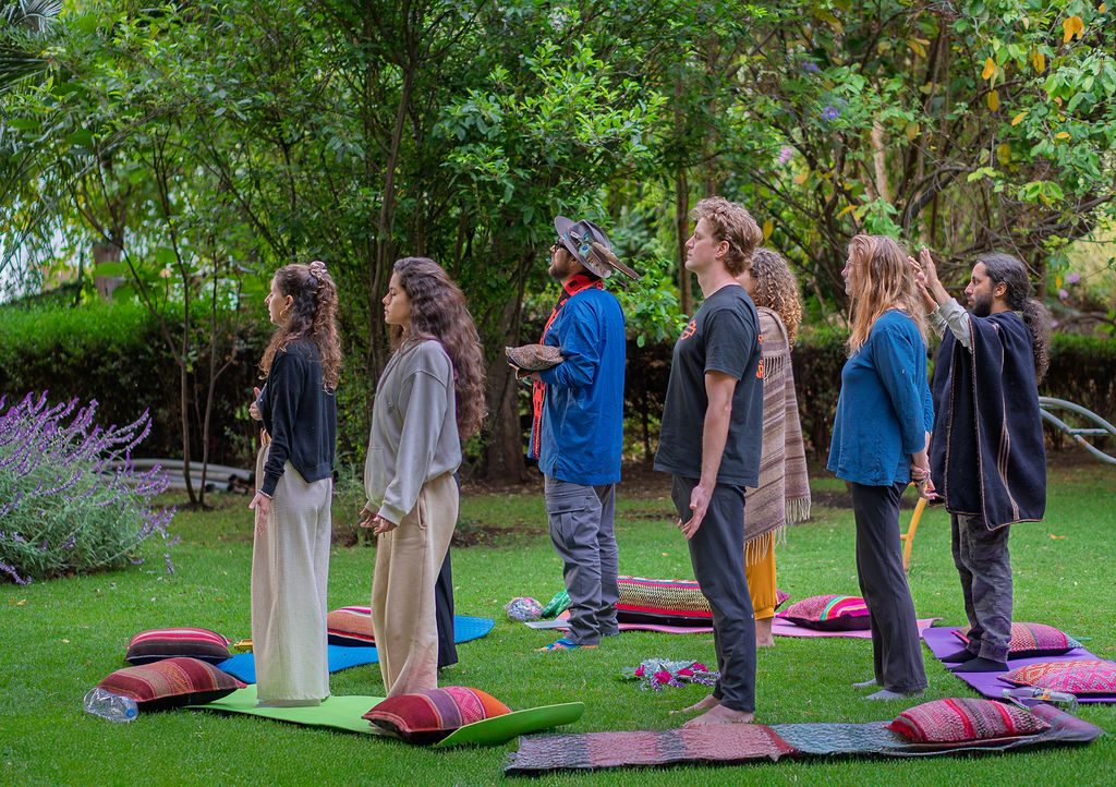 Participants stand in a circle on cushions in the garden