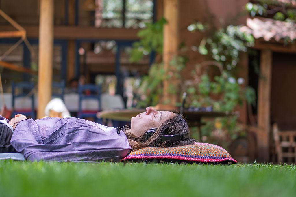 A participant rests on the grass with headphones on