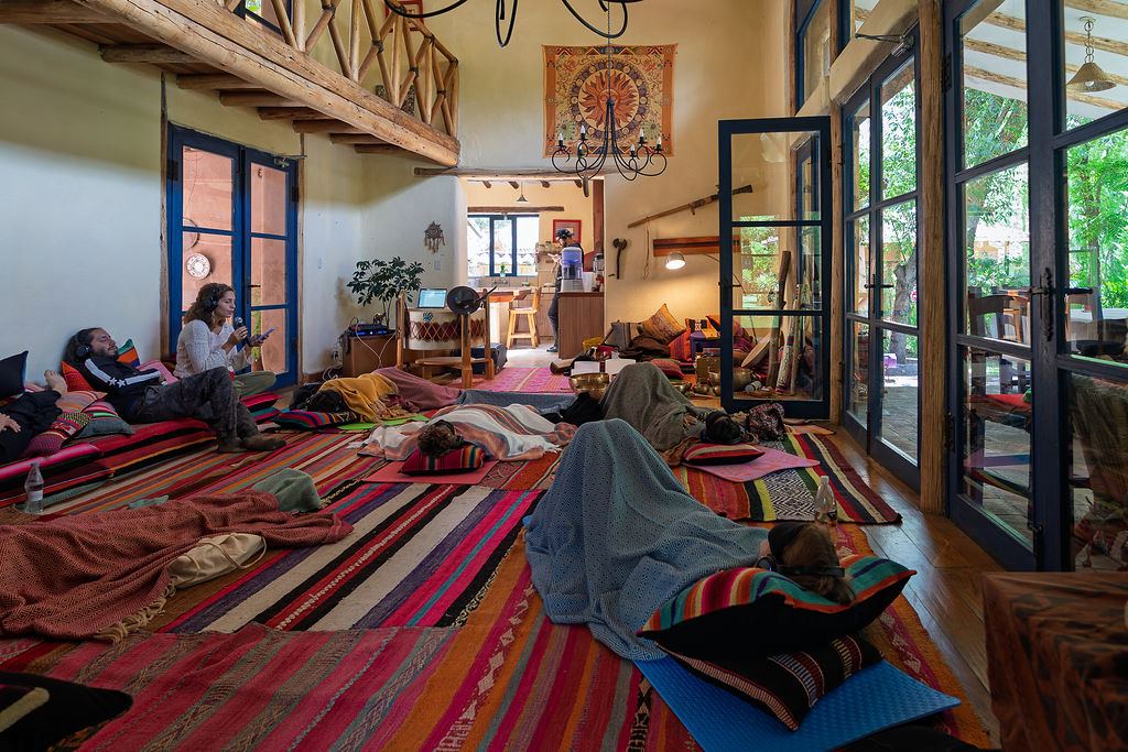 Wide view of the shala with colourful rugs and tall windows onto the garden