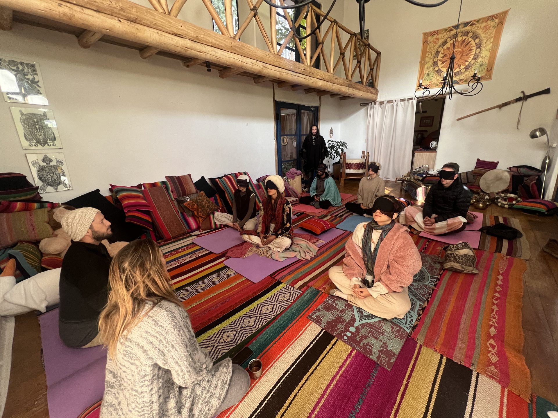 The group sits in meditation on striped Andean rugs inside the shala