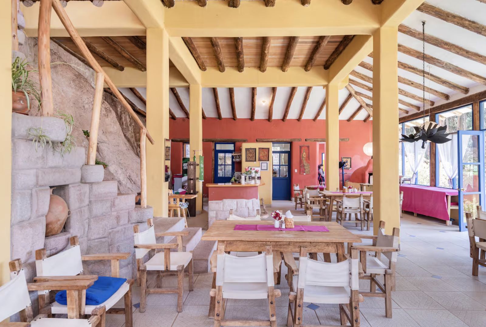 Open dining terrace with wooden tables beside a stone wall