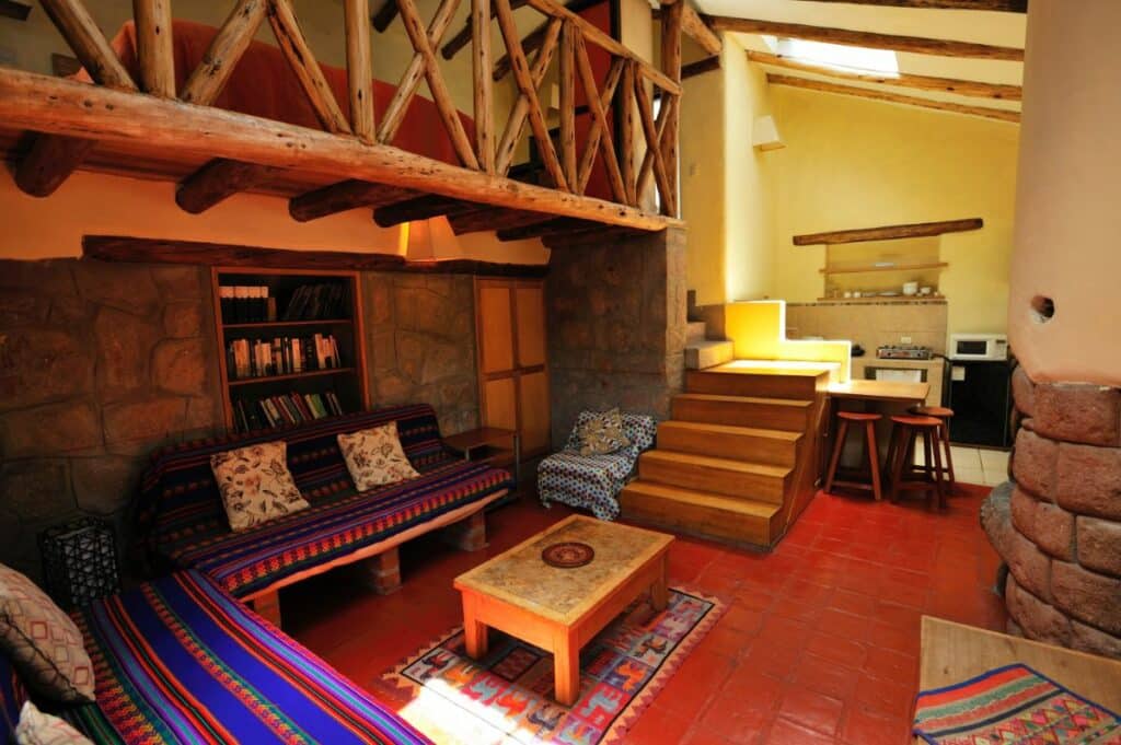 Bungalow living area with sofa, coffee table and loft stairs at Melissa Wasi in Pisac