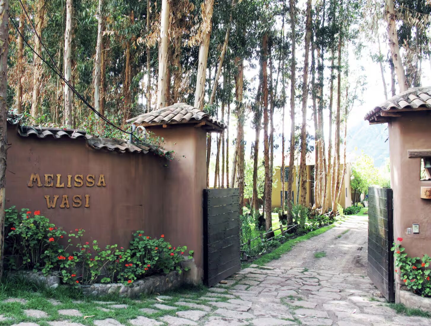 The Melissa Wasi gate among flowers and eucalyptus